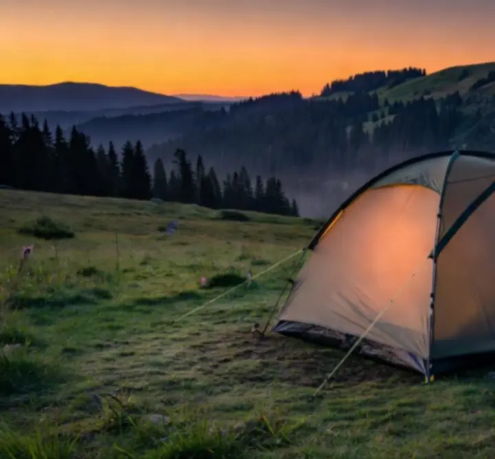 Malowniczy krajobraz dzikiej przyrody z obozowiskiem w górskiej dolinie o zachodzie słońca